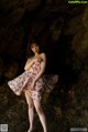 A woman in a floral dress standing in a cave.